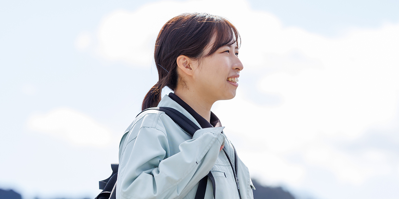 Y.N.さんが鞄を持って、外で立っている様子
